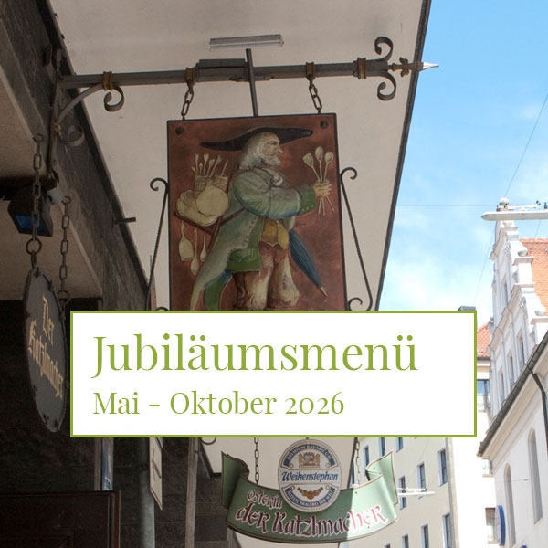 Decorative hanging sign on a street with a medieval painter image; overlay text reads Jubiläumsmenü Mai - Oktober 2026.